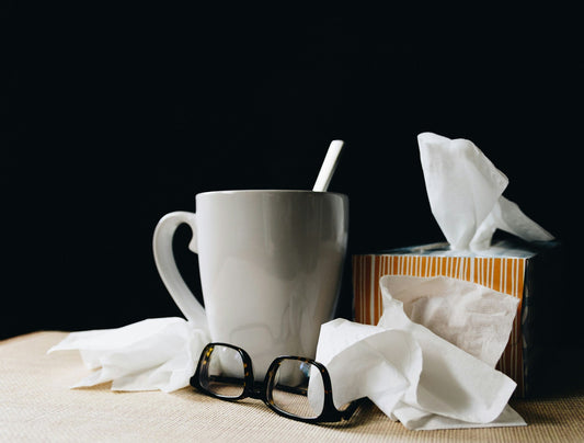 Tissues, tea, and glasses of someone with a cold or flu