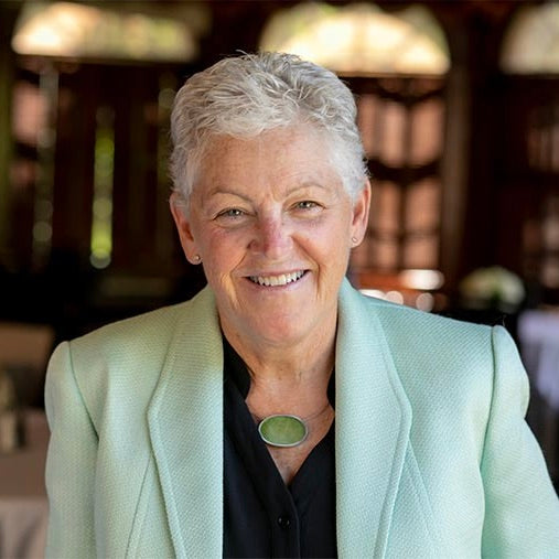 headshot of woman wearing black blouse and light green jacket