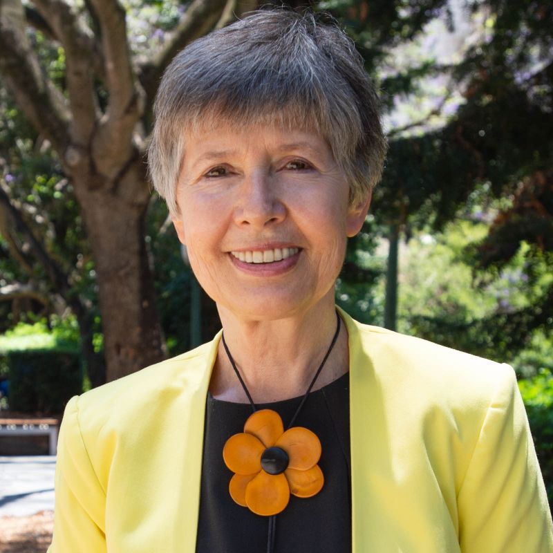 woman wearing black shirt, yellow jacket and flower bolo necklace